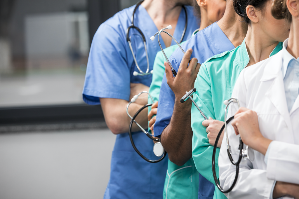 Nurses standing in a line, each holding a stethoscope